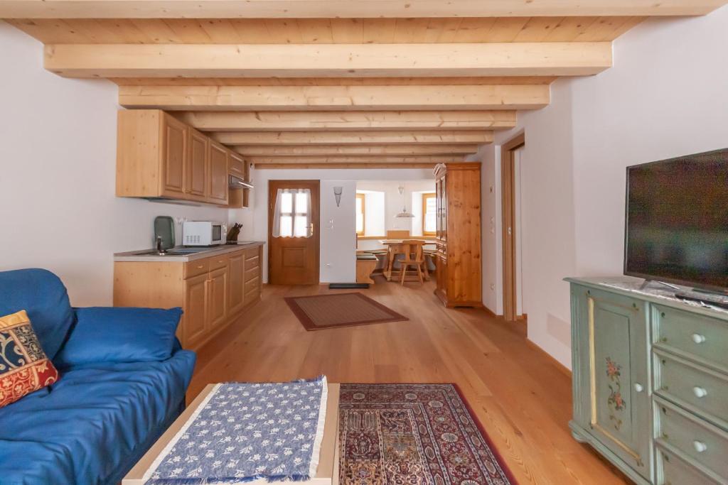 a living room with a blue couch and a kitchen at Casa Piccolin in Falcade