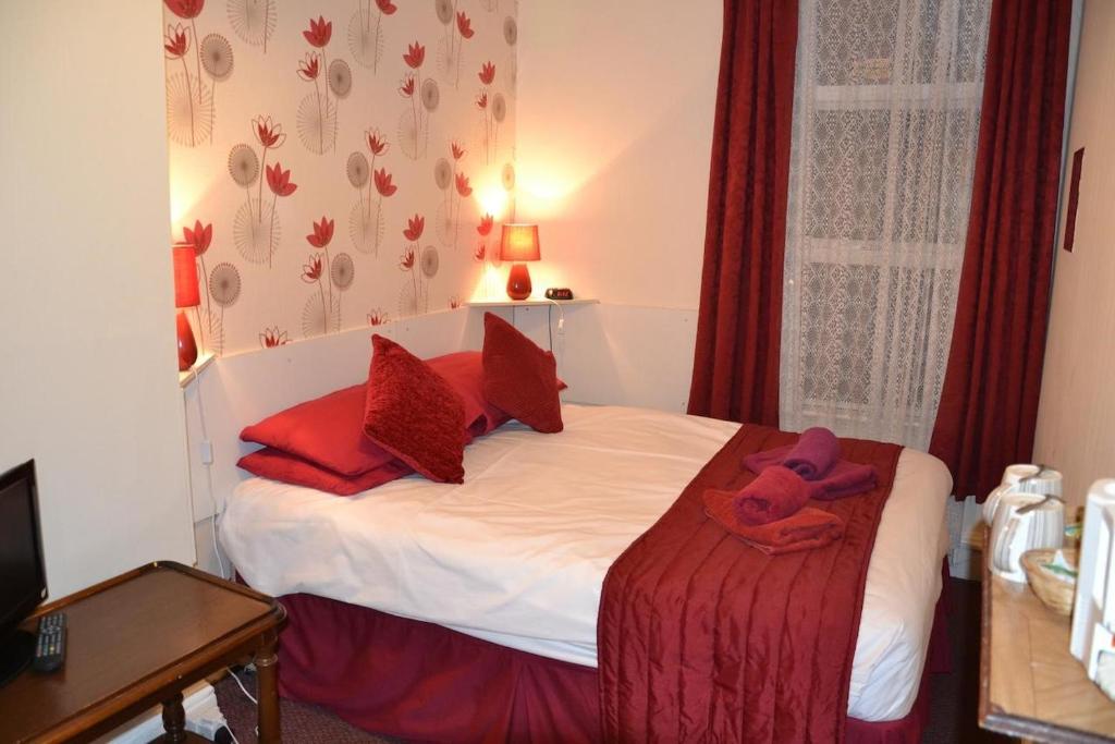 una piccola camera da letto con letto con cuscini rossi di Chiswick Lodge Hotel a Londra