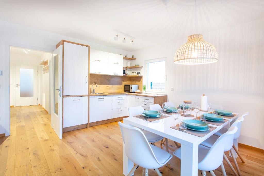 a white kitchen with a white table and chairs at Alpine Home Apartment in Bohinj