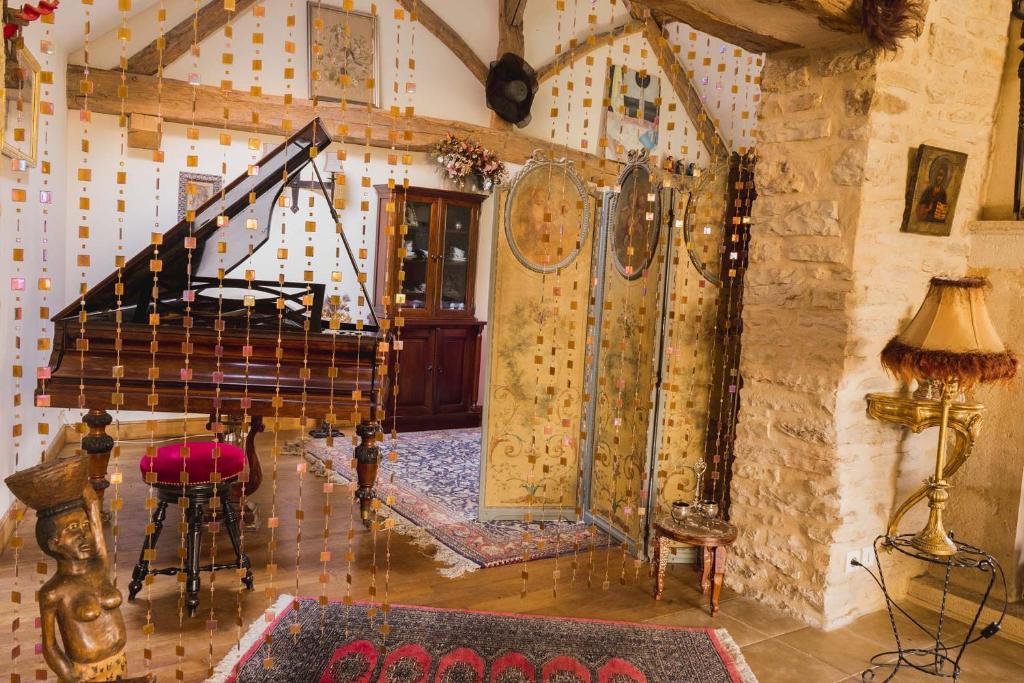 a living room with a grand piano in a room at La Cuverie du Château in Corcelles-les-Arts