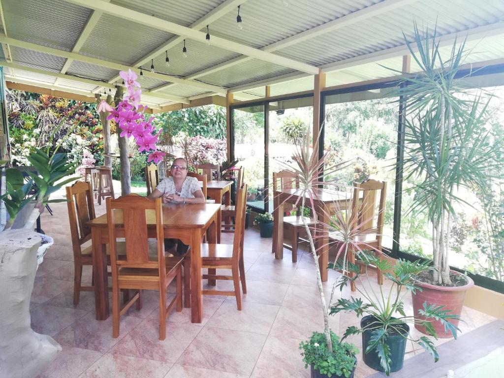 a man sitting at a table in a room with plants at Marita's Bed and Breakfast in Nuevo Arenal