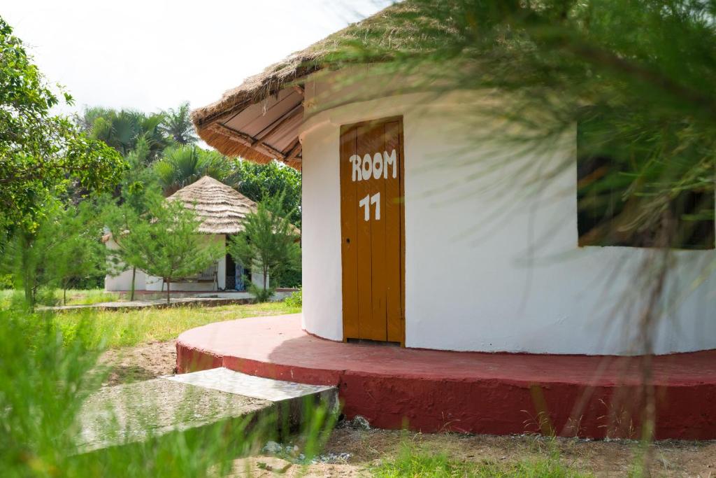 Folonko的住宿－Tamba Kuruba Eco-lodge，一座白色的小建筑,上面有棕色的门