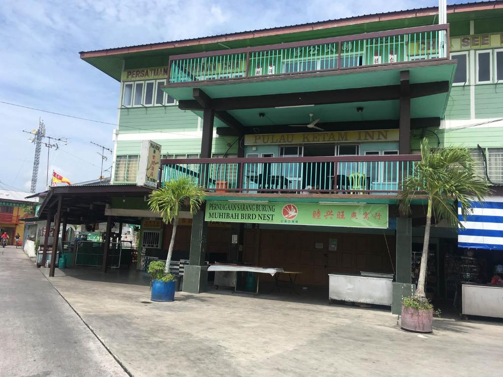 a building with palm trees in front of it at Sea Lion Pulau Ketam Inn in Bagan Teochew