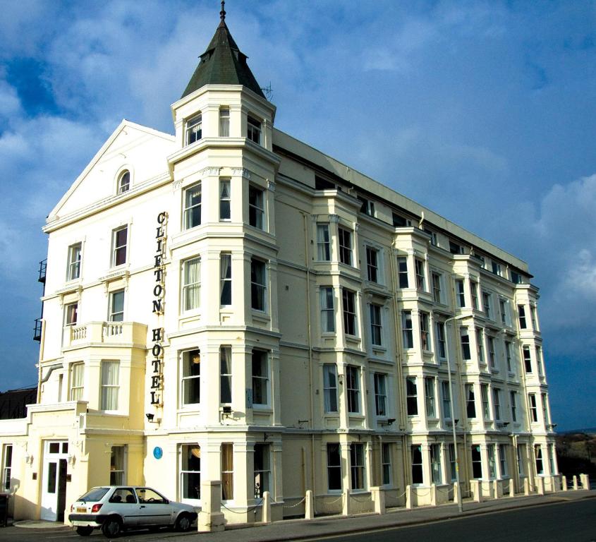 Un bâtiment blanc avec une voiture garée devant. dans l'établissement Clifton Hotel, à Scarborough