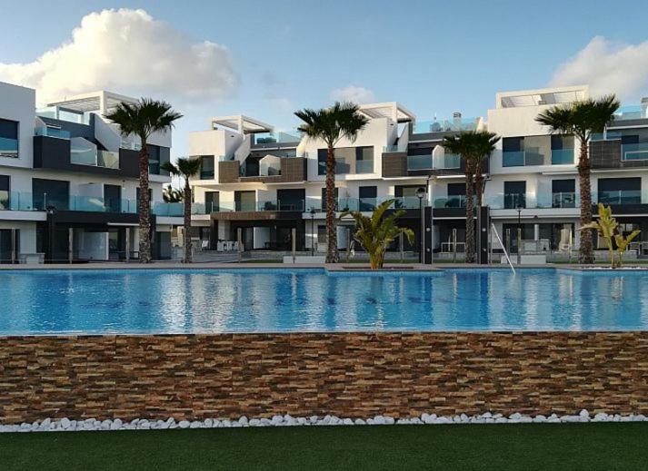 une grande piscine avec des palmiers en face d'un bâtiment dans l'établissement Oasis Beach X 106, à Guardamar del Segura