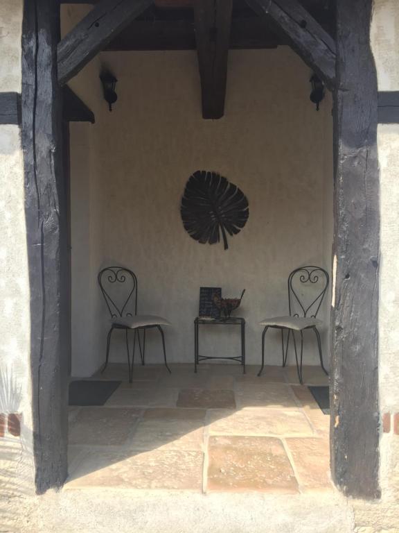 two chairs and a table with a fan on the wall at Le Moulin de Champagne in Viriat