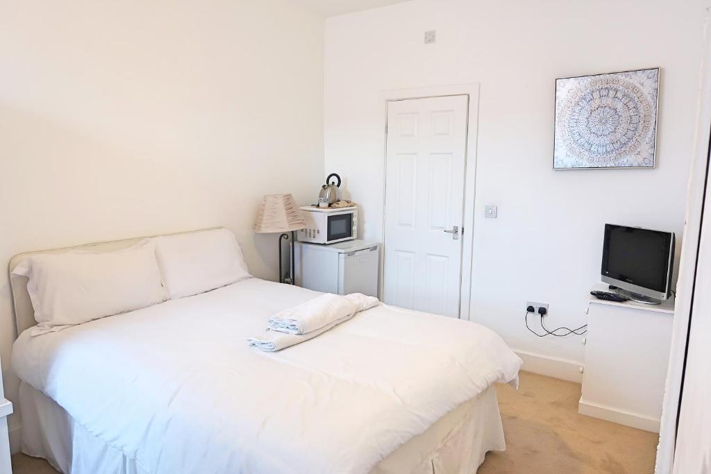 een witte slaapkamer met een bed en een televisie bij Whitburn Guest House About 7 mins Walk To The City Free Internet TV in Doncaster