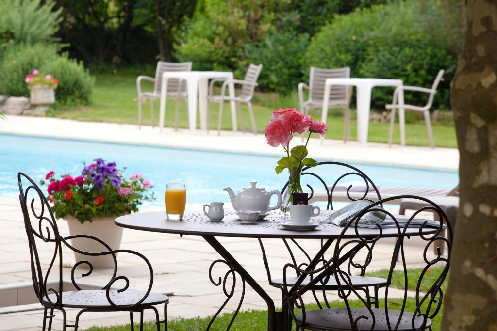 einen Tisch mit einer Blumenvase neben einem Pool in der Unterkunft Logis Auberge Saint Simond in Aix-les-Bains