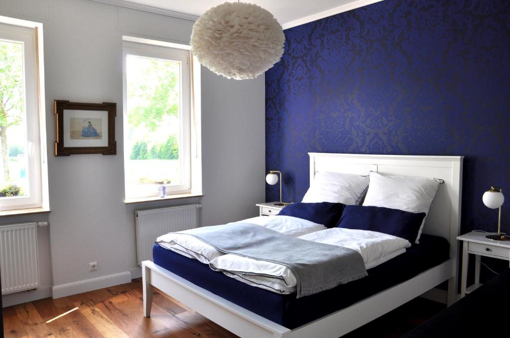 a blue bedroom with a bed and two windows at Maison Elise & Philipp in Wiesbaden