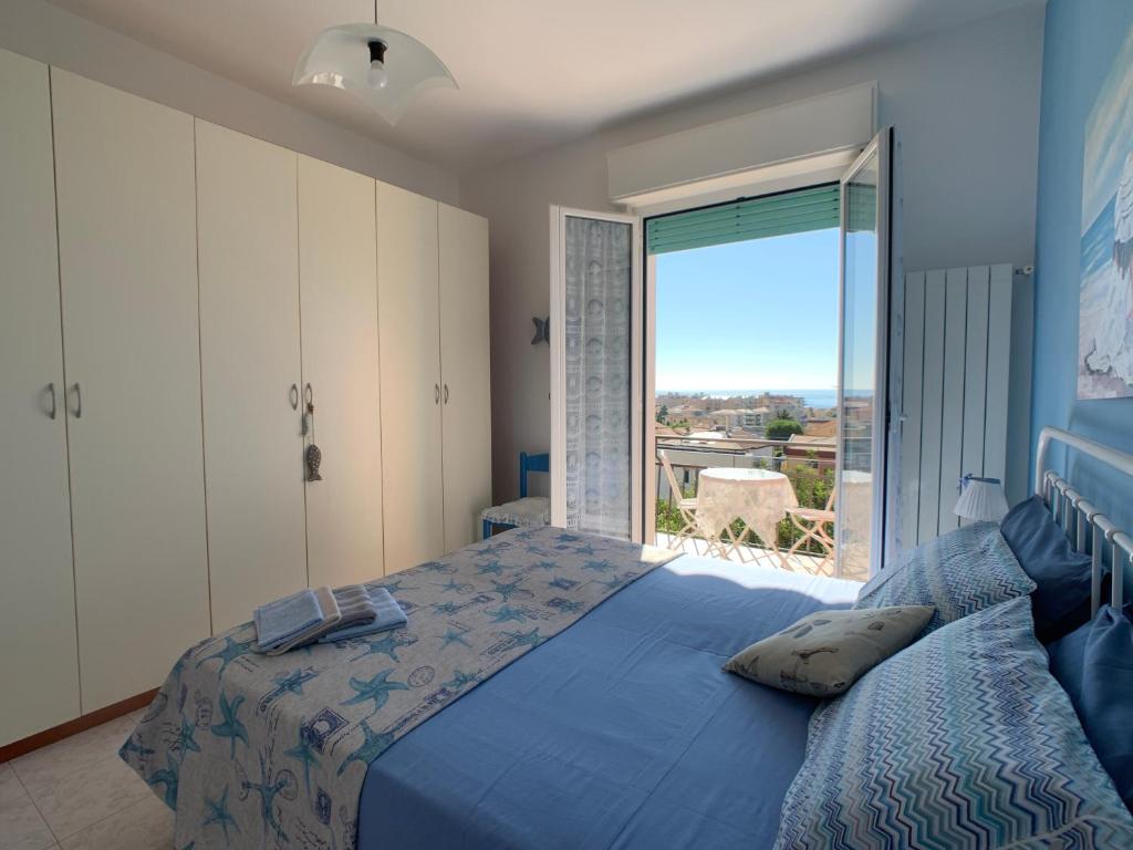 a bedroom with a blue bed and a large window at Very cosy house with fabulous sea view! in Pietra Ligure