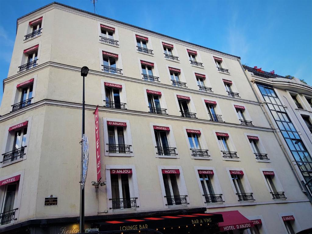 een groot wit gebouw met veel ramen aan een straat bij Hôtel D'Anjou in Levallois-Perret