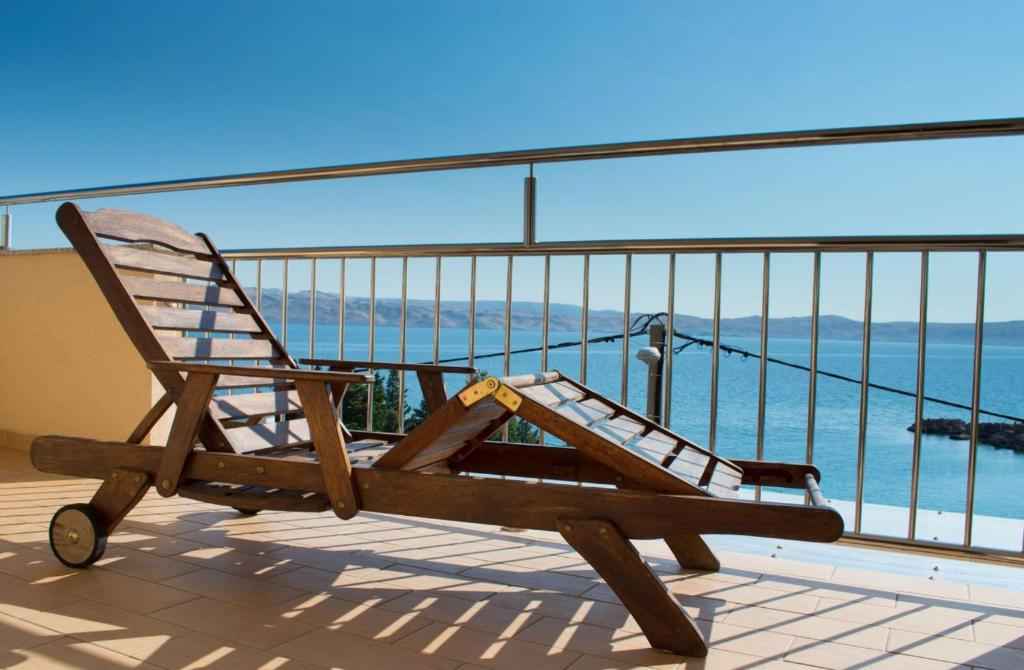 einen Schaukelstuhl auf einem Balkon mit Meerblick in der Unterkunft Apartments Ribarica in Karlobag
