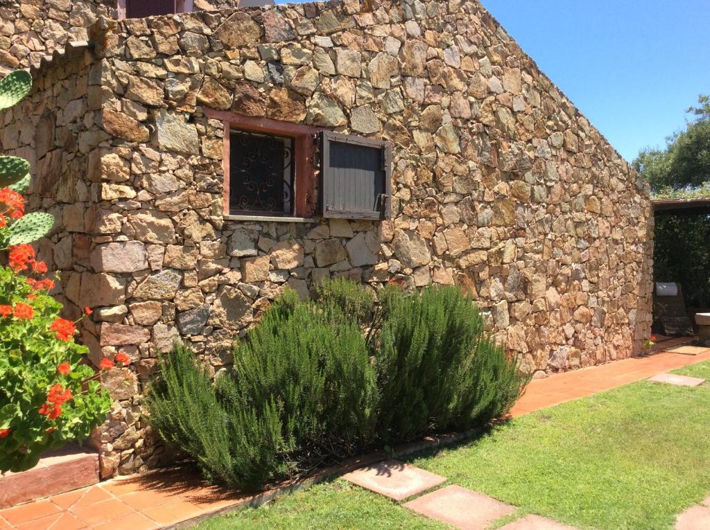 un bâtiment en pierre avec une fenêtre et quelques plantes dans l'établissement Villa Bea, à Chia