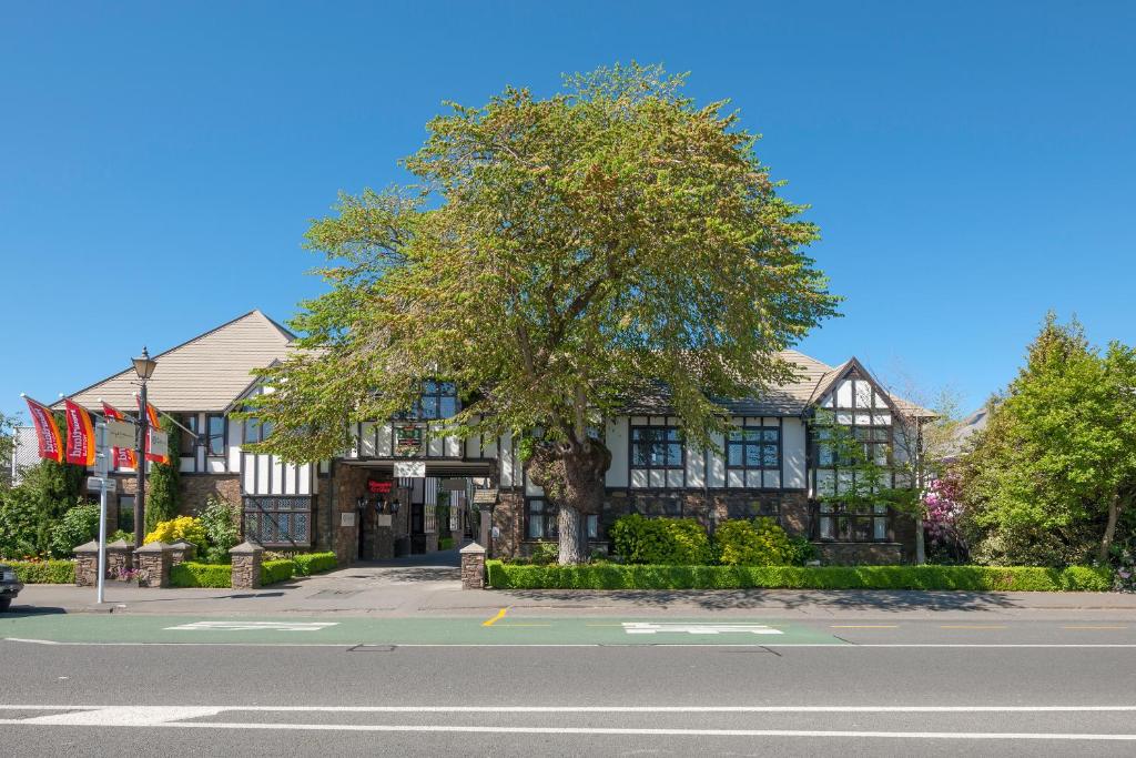 a building with a tree in front of a street at Scenic Hotel Cotswold in Christchurch