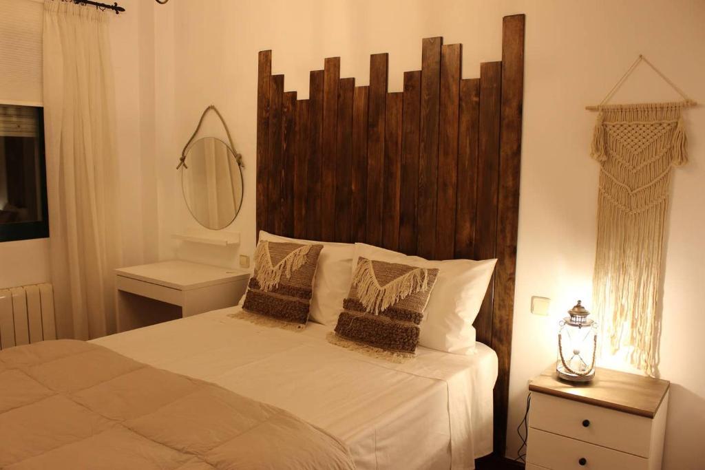 een slaapkamer met een groot bed met een houten hoofdeinde bij Casa Rialto in Olivenza