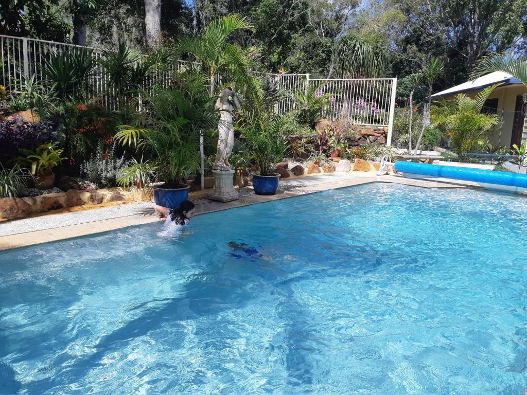 a woman swimming in a swimming pool at Mapleton Peaceful Provence BnB in Mapleton