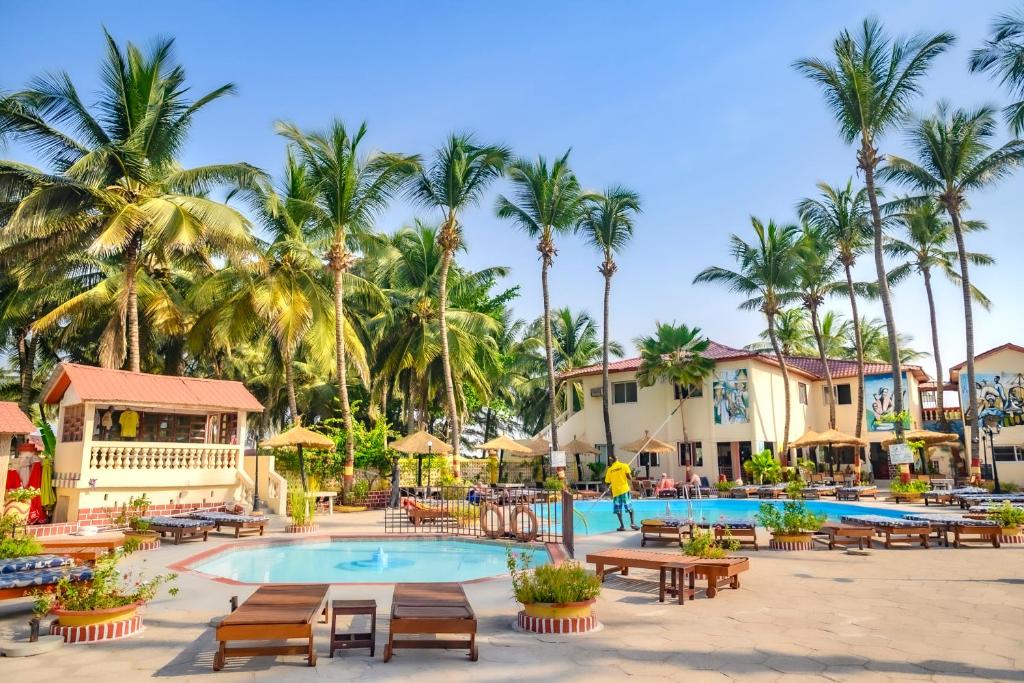 a resort with a pool and tables and palm trees at Palm Beach Hotel in Kotu