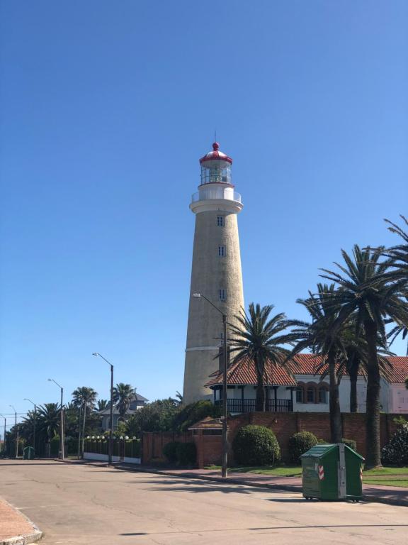 a lighthouse on the side of a street with palm trees at Apartamento 4 Mares - El Faro in Punta del Este