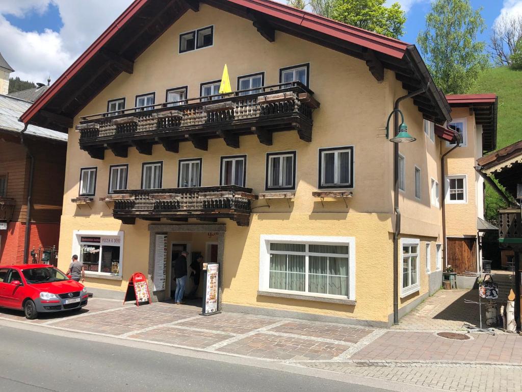 ein rotes Auto, das vor einem Gebäude parkt in der Unterkunft Pension Reiterhaus in Wagrain