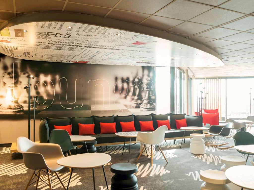 a waiting room with tables and chairs and graffiti on the wall at Ibis Schiphol Amsterdam Airport in Badhoevedorp