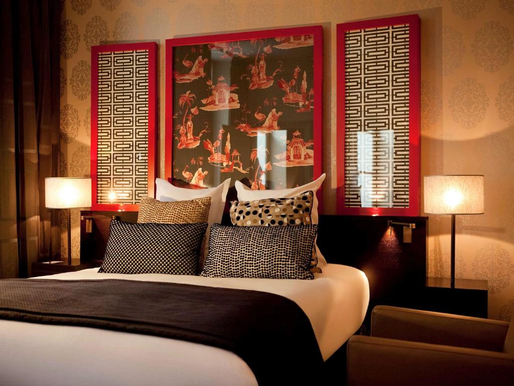 a bedroom with a bed with two lamps and a painting at Le Stendhal - Vendôme in Paris