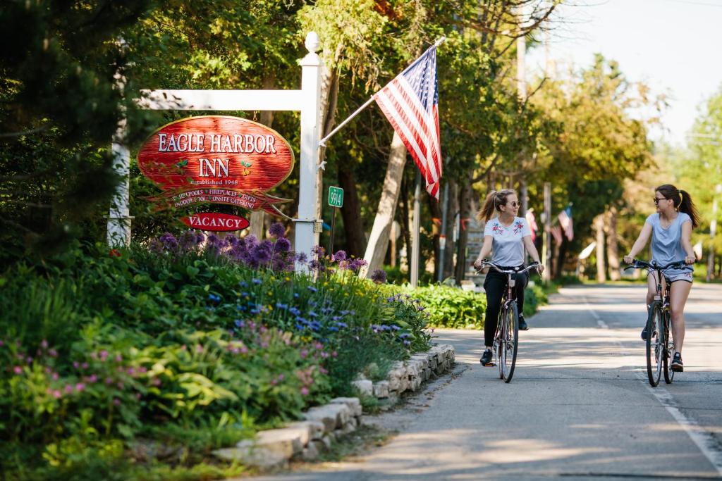 two girls riding bikes down a street with an american flag at Eagle Harbor Inn in Ephraim