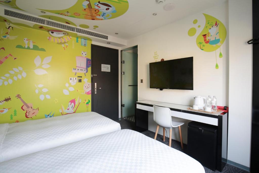a bedroom with a bed and a desk and a tv at CityInn Hotel Plus - Taichung Station Branch in Taichung