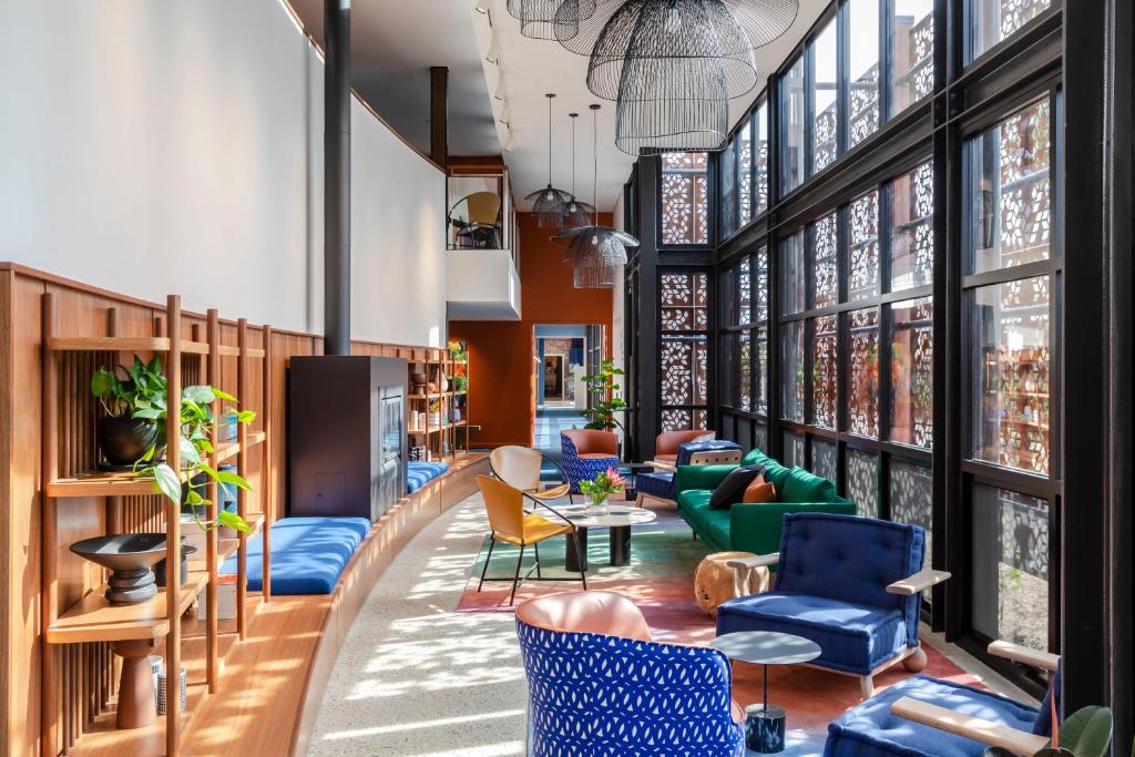 a lobby with blue chairs and tables and windows at Byng Street Boutique Hotel in Orange