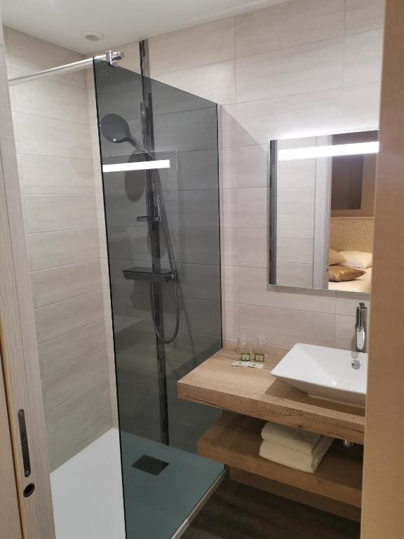 a bathroom with a shower and a sink at Logis Hotel Des Bains in Gérardmer