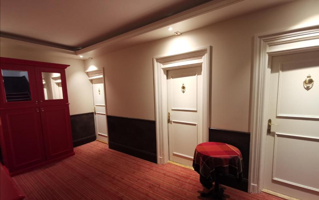 a hallway with a red door and a red stool at Logis Hotel Des Bains in Gérardmer