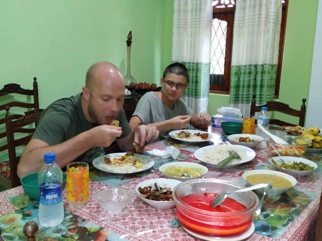 キャンディにあるLalanga Homestayの二人がテーブルに座って食べ物を食べる