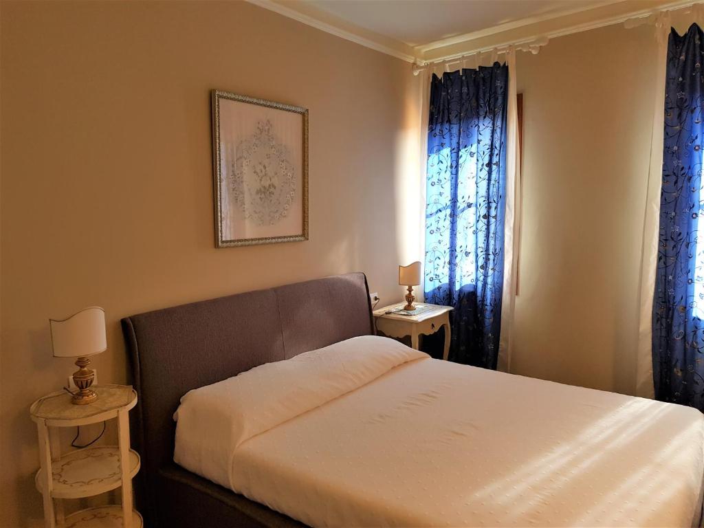 Schlafzimmer mit einem Bett und einem Fenster mit blauen Vorhängen in der Unterkunft Cà Melidissa in Venedig