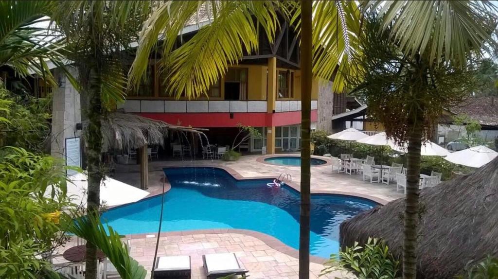 a swimming pool in front of a resort with palm trees at Ilhaflat 3-104 in Ilhabela