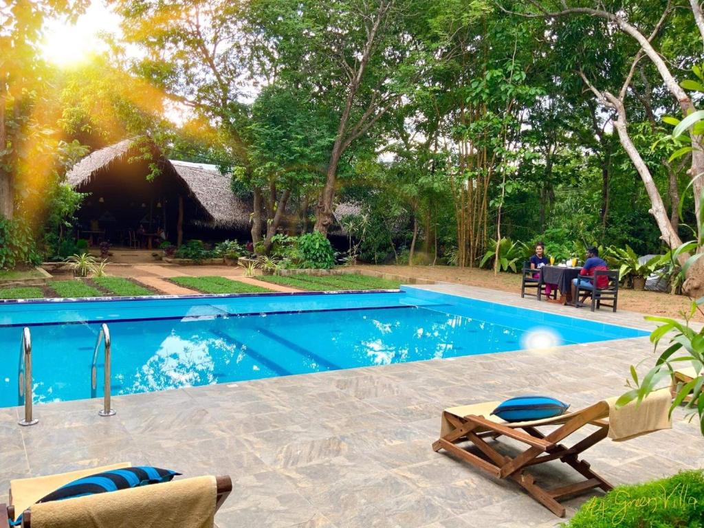 a swimming pool with people sitting at a table near a resort at A4 Villa & Spa. in Habarana