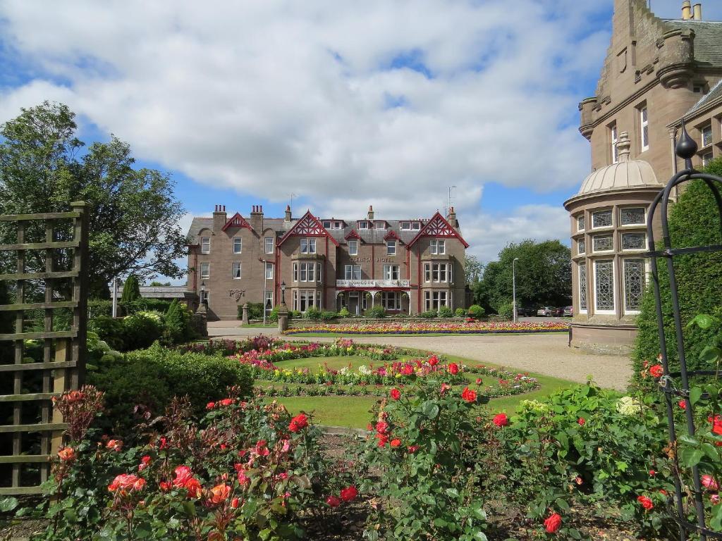 a large building with a garden and flowers at Glenesk Hotel in Edzell