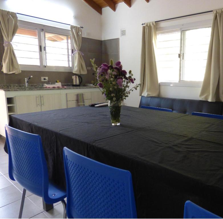 una mesa negra con sillas azules y un jarrón de flores en El Álamo en Merlo