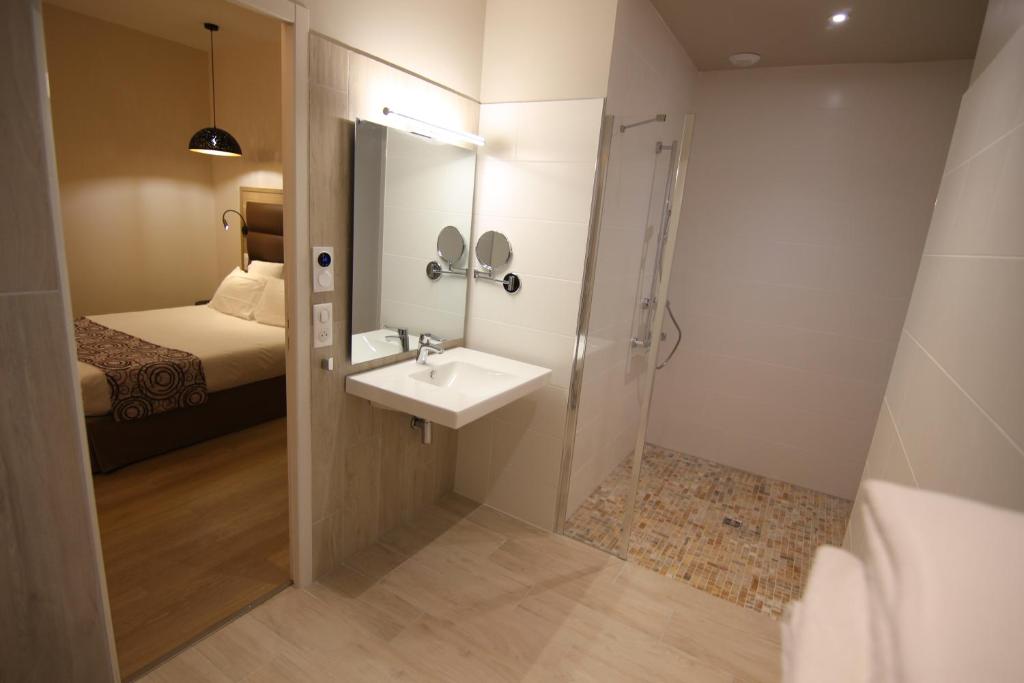 a bathroom with a sink and a shower and a bed at Hôtel Montaigne in Sarlat-la-Canéda