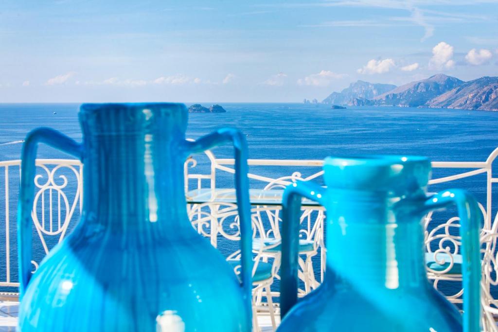 three blue vases sitting on a balcony overlooking the ocean at Hotel Smeraldo in Praiano