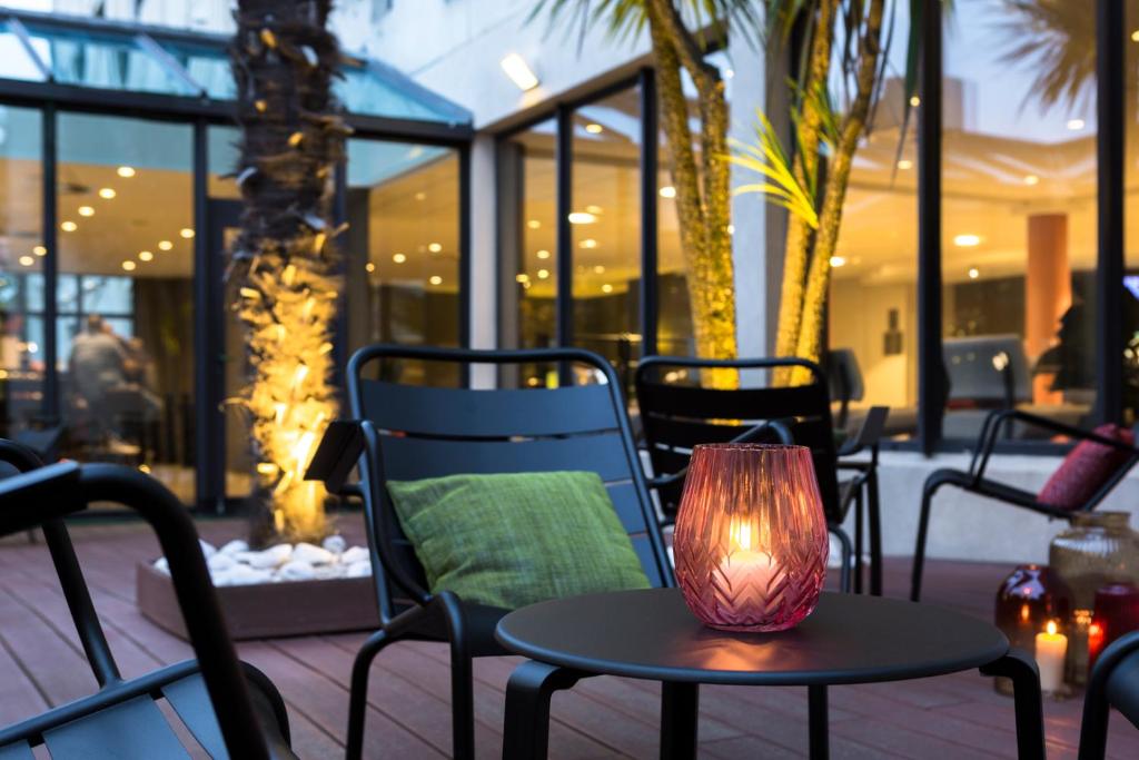 a table with a lamp sitting on a patio at Hôtel Oceania Nantes Aéroport in Bouguenais