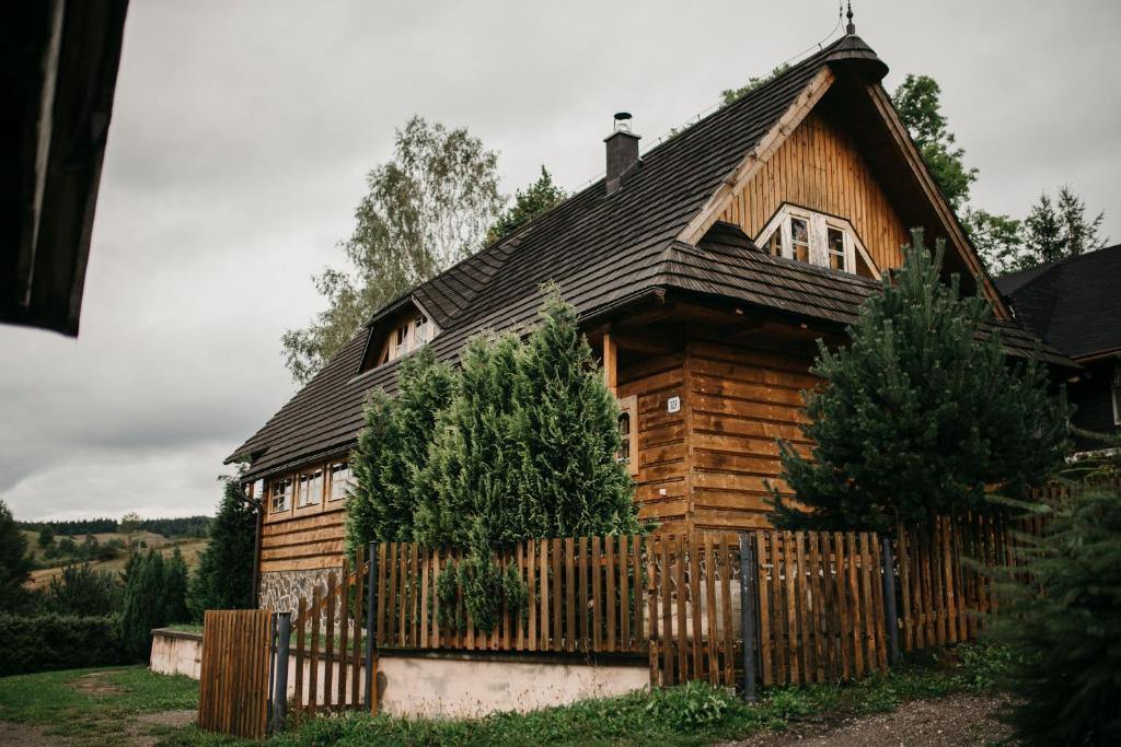 a wooden house with a fence in front of it at Chalupa pod Skleným Vŕškom in Huty