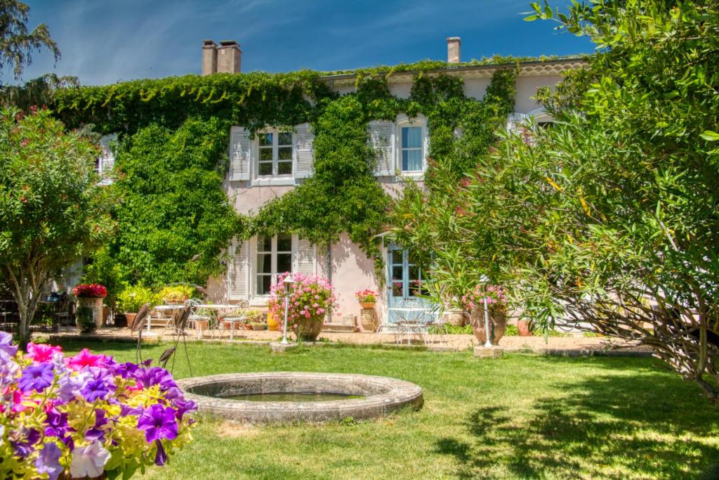 une maison avec un jardin et des fleurs dans la cour dans l'établissement Mas d'Escattes, à Nîmes