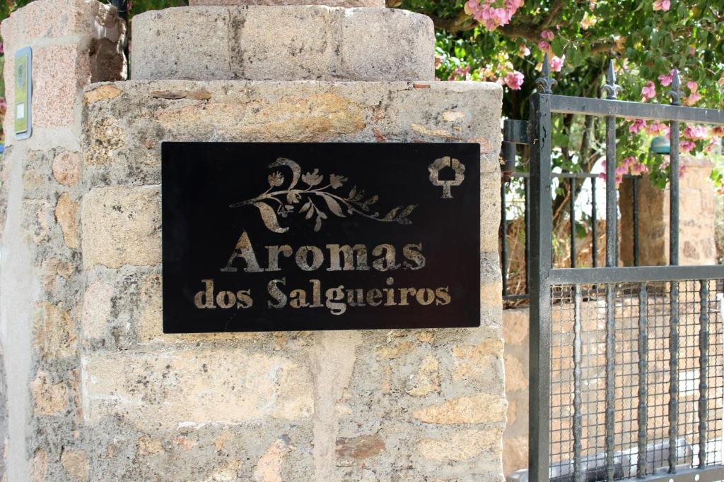 een bord op een stenen muur naast een poort bij Aromas dos Salgueiros in Castelo de Vide