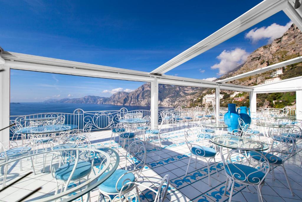 a balcony with tables and chairs and the ocean at Hotel Smeraldo in Praiano
