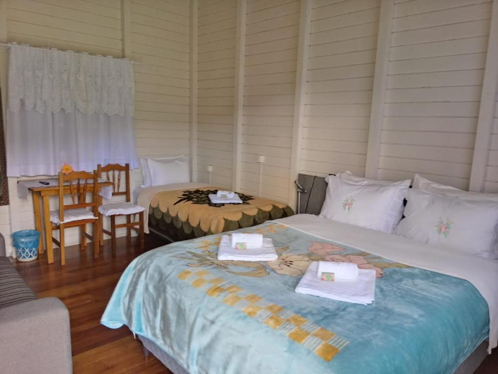 a bedroom with two beds and a table and chairs at Pousada Landhaus in Urubici