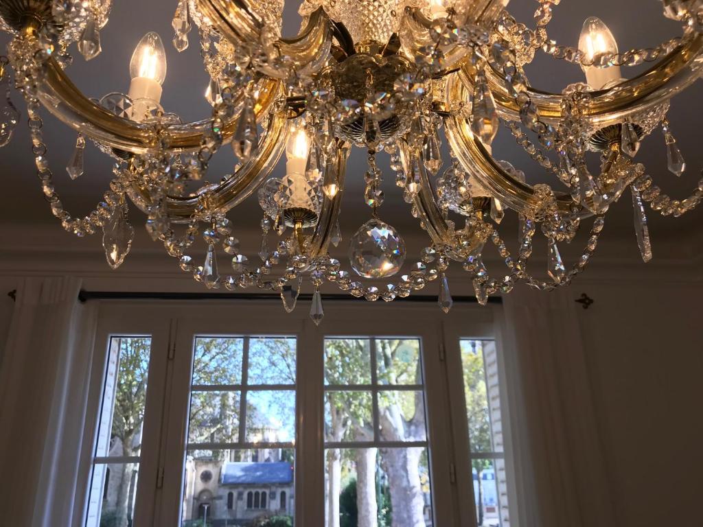 een grote kroonluchter in een kamer met een raam bij Luxurious Townhouse in the Heart of Champagne in Épernay