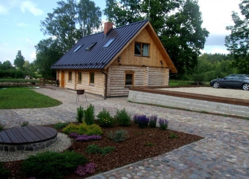 una pequeña casa de madera con un jardín delante de ella en Vilks un Briedis Holiday Home & Wellness Area, en Smiltene