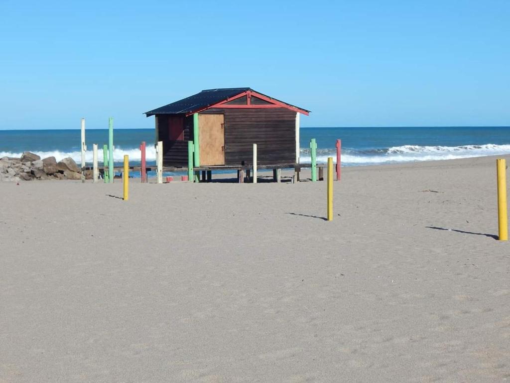 a shack on a beach with yellow poles in the sand at DEPARTAMENTO MIRAMAR in Miramar
