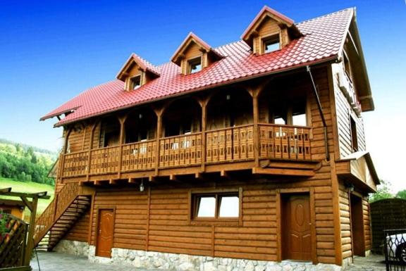 een groot houten huis met een groot terras bij Nad Potokiem in Kaczorów