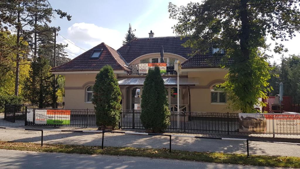 une maison avec une clôture devant elle dans l'établissement The Corner House Panzió, à Tata