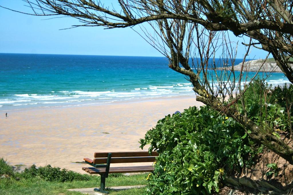 a bench sitting on the beach near the ocean at 19 Ocean Gate in Newquay